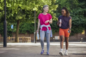 Two women walking and talking outdoors in exercise clothes